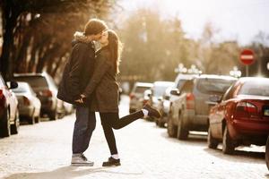 chico y la chica besándose en la calle de la ciudad foto