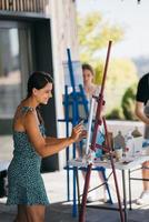 Young woman artist paints with a spatula on the canvas photo