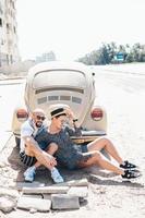 Couple sitting on the asphalt behind the car photo