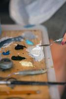 Close up of woman's hand mix paints in palette in art-class photo