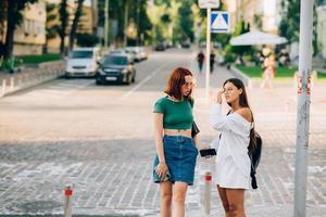 Two tourist friends consulting an online guide on a smart phone in the street photo