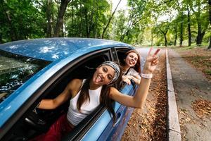 Two girlfriends fool around and laughing together in a car photo