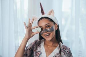 Funny smiling Spa Woman with fresh Facial Mask hold cucumber. photo