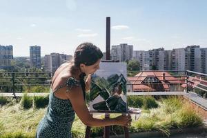 joven artista pinta contra el fondo de la ciudad foto