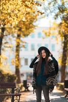 mujer elegante en poncho y sombrero disfruta del parque de otoño foto