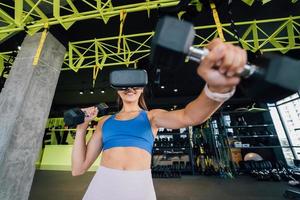 Woman wearing glasses of the virtual reality exercising with dumbbells photo