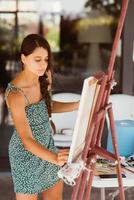 Young woman artist paints with a spatula on the canvas photo