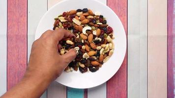 Man picks up handful of trail mix from plate video