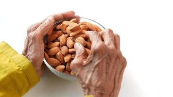 des mains âgées cueillent des amandes dans un bol video