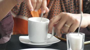 mujer revolviendo una taza de café con una cuchara pequeña, de cerca video