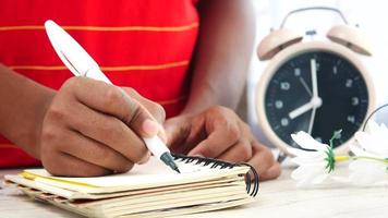 escribir en un planificador con bolígrafo y un reloj en el fondo video