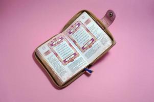 Sangatta, Indonesia, 2018 -  an open page of Quran shows surah al faiha and al baqarah on pink background. Quran is an Islamic holy book for muslim. photo