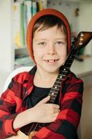 boy in a red hat and a plaid shirt plays the balalaika. photo
