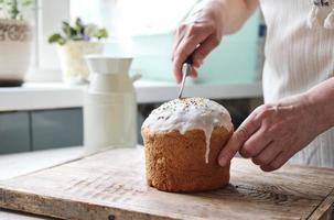 postre tradicional ruso de requesón de pascua. manos de mujer toman un pedazo de paskha ortodoxa. tortas kulich en la mesa. fondo bokeh de flores. foto