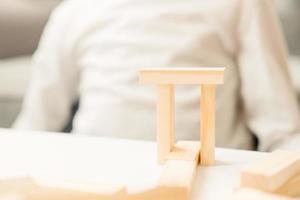 hands of a boy close-up, in a white t-shirt, builds a house, on the table. Board games for children and adults. A pastime without gadgets. Vacation games at home. child plays with wooden cubes. photo