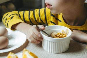 niño desayuna por la mañana con cereales con leche. primer plano de copos foto