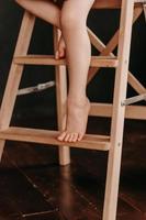 children's feet dangle from the stool. Photo in brown tones.