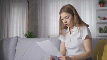 traurige, am Boden zerstörte junge Frau, die Papier betrachtet. die junge Frau, die unglücklich und traurig über das Papier ist, das sie betrachtet. video