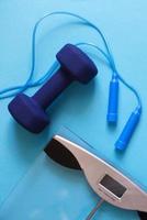 Flat lay composition with weigh scales, skipping rope and dumbbells isolated on blue background.Healthy active lifestyle photo