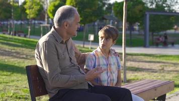 großvater plaudert mit enkelkind. großvater und enkelkind unterhalten sich im freien. video