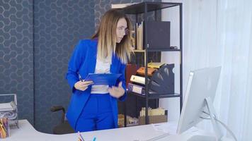 Creative young businesswoman using laptop at office desk and taking notes. Young business woman working in office, taking notes, looking at computer. video