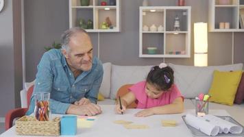vovô estudando com seu neto no caderno e livro. o avô está ensinando com seu neto. video