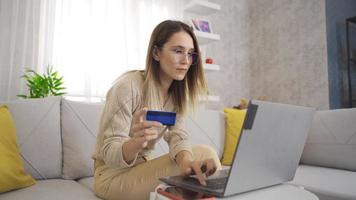 giovane donna a casa shopping con un' credito carta. giovane donna shopping su il computer portatile entra credito carta informazione. video