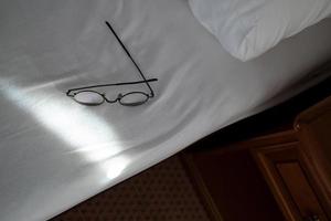 Glasses are left carelessly on the edge of the bed and can fall and break. Concept of careless attitude to things. photo