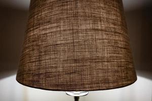 Beige shade of the floor lamp dims the light and creates a calm atmosphere in the bedroom. photo