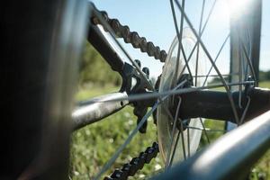 detalle de primer plano de una bicicleta estacionada en un prado, contra el telón de fondo del sol y el cielo azul. concepto de estilo de vida activo. vista inferior. foto