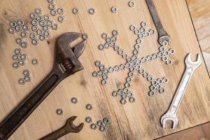Snowflake made of metal nuts and wrenches on a wooden table. Winter symbol. New Year and Christmas holiday wait concept. Top view. photo