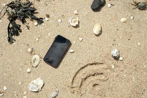 la señal de wi-fi se dibuja en la arena junto a un teléfono inteligente, en la orilla del mar, en un día soleado de verano. vista superior. foto