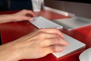 Female hands work with a keyboard and a touchpad, a computer is nearby. Remote work. Contemporary workplace and lifestyle. photo