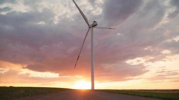 Windmill is spinning against the backdrop of a beautiful sunset sky. Renewable energy production for green ecological world. Alternative energy concept. Wind power plant. video