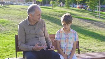 Grandfather and grandchild chatting outdoors. Old man chatting with his grandson in the park. video