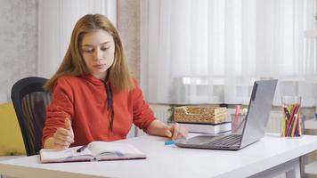 Stressed schoolgirl is bored of looking at books. Schoolgirl looking at her books volupto at home and getting bored. video