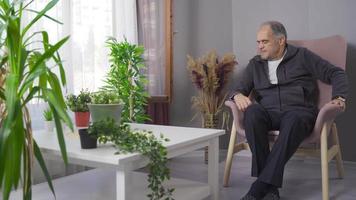 Grandpa living alone is sad and resentful. The old man is sad and looks out the window. video