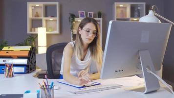 la mujer de negocios está completando el proyecto en el que está trabajando y relajándose. la joven mujer de negocios que hace bien su trabajo está feliz y relajada. video