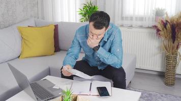 Man looking at bills at home calculating with calculator. Working man trying to pay bills. video