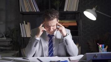 Stressed and thoughtful businessman working on a project at night. Businessman working alone on a project at night. video