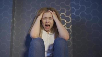 gritando jovem. mulher infeliz, deprimida e psicologicamente perturbada. jovem mulher encostada na parede gritando gritando e chorando. video