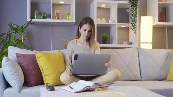 vrouw werken met laptop Bij huis. jong vrouw zittend Aan sofa Bij huis werken met laptop. video