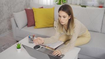estudiante usando laptop en casa. mujer joven sentada en una acogedora sala de estar y usando una computadora portátil en casa. video