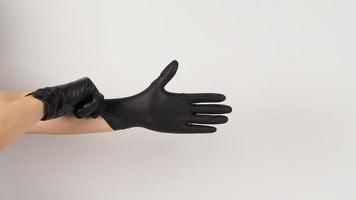 The hand is pulling black latex gloves  on white background. photo