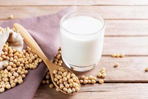leche de soja en un vaso con soja en una mesa de madera desayuno orgánico, alto en proteínas, productos agrícolas saludables, vegetariano foto