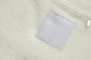 Blank white laundry care clothes label on fabric texture background photo