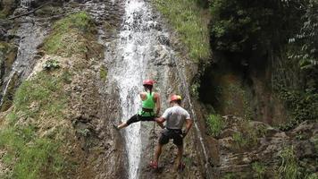 video hd de dos personas, un hombre y una mujer, haciendo escalada en una cascada que cae. santa catarina, puebla