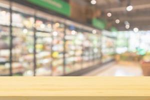 Empty wood table top with supermarket grocery store aisle and shelves blurred background photo