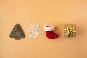 Handmade crochet stocking ,gift and christmas tree on orange pastel background. Merry Christmas and happy new year concept. photo