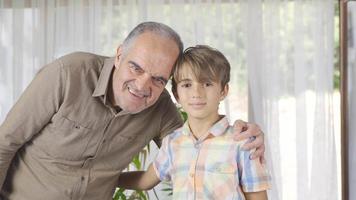 Smiling grandfather and grandchild who looks at camera. Sympathetic grandfather and grandson looking at camera. video